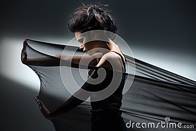 Brunette stretches stretch mesh fabric in front of Stock Photo