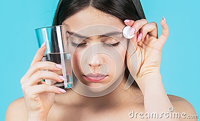 Brunette taking a pill with a glass of water. Woman taking drugs to releave headache. Brunette take some pills, holds Stock Photo