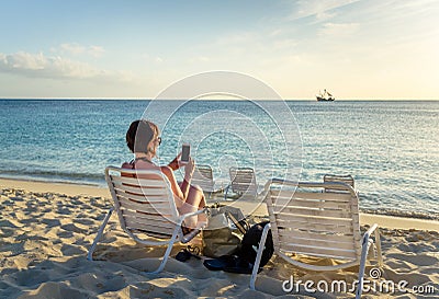 Brunette Using her Mobile Phone on the Beach Stock Photo