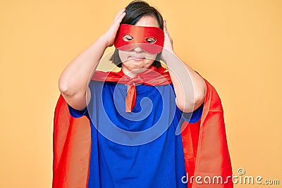 Brunette woman with down syndrome wearing super hero costume suffering from headache desperate and stressed because pain and Stock Photo