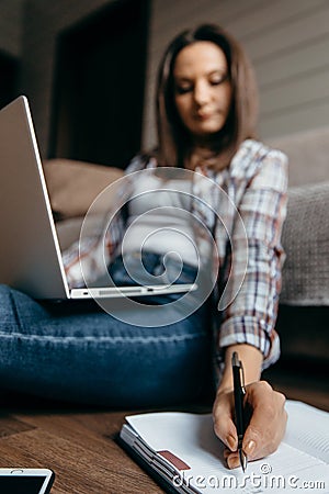 Brunette woman sitting on the floor with laptop and take note left hand. Stock Photo
