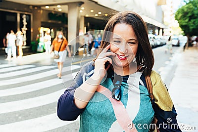 Brunette woman wearing casual clothes standing on a street in Valencia, Spain, talking on mobile phone Stock Photo