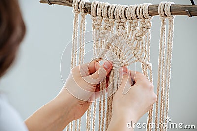 Craftswoman weving ropes, creating a macrame banner. from behind Stock Photo