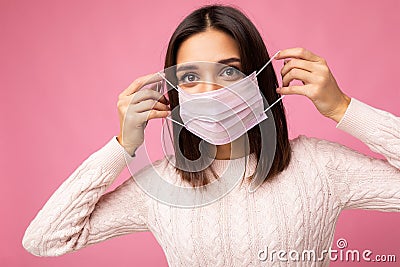 Brunette young woman holds and wears a white medical mask to protect yourself from corona virus, cares for her health Stock Photo