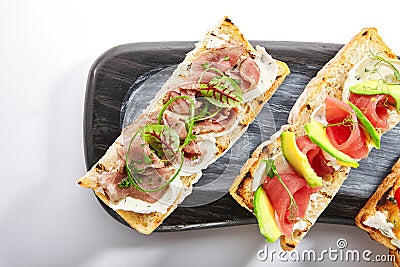 Bruschetta with baked pepper, tuna, avocado and pastrami Stock Photo
