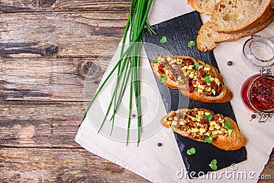 Bruschetta with feta cheese, dried tomatoes, olive oil and fresh microgreen herbs, on a stone plate on a wooden table. Stock Photo