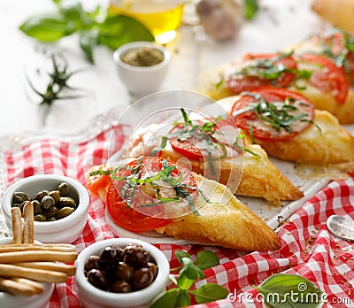 Bruschetta, grilled slices of baguette with mozzarella cheese, tomatoes, garlic and aromatic basil on a white wooden table Stock Photo