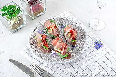 Bruschetta with rye bread, prosciutto, cream cheese, capers and salad leaves Stock Photo