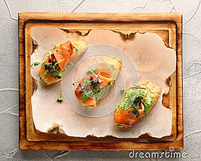 Bruschetta with salmon on wood top view. Smoked salmon toast with guacamole and microgreen Stock Photo