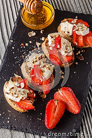 Bruschetta with strawberries, blue cheese, walnut and honey on stoyn plate Stock Photo