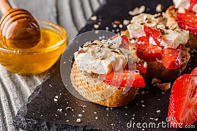 Bruschetta with strawberries, blue cheese, walnut and honey on stoyn plate Stock Photo