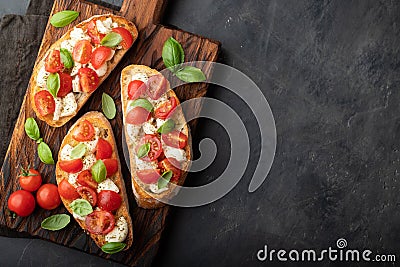 Bruschetta with tomatoes, mozzarella cheese and basil on a cutting board. Traditional italian appetizer or snack, antipasto. Top v Stock Photo