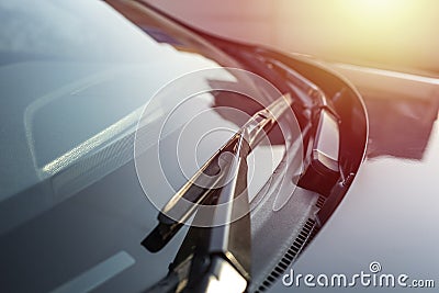 Brushes on the car glass with copy space. The work of windshield wipers - brushes and an evening sunbeam. Stock Photo