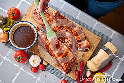 Brushing Pork Ribs with marinade sauce on Wooden Cutting Board Stock Photo