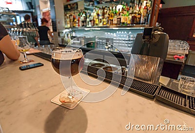 Craft beer in old stylish glass on bar counter of restaurant with visitors and bartenders Editorial Stock Photo