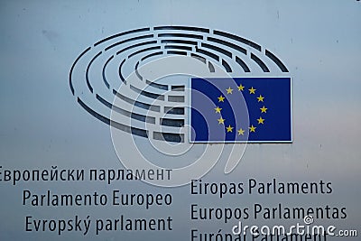 Multilingual sign and EU flag on European Parliament building in Brussels Editorial Stock Photo