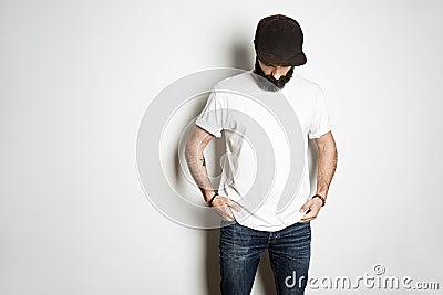 Brutal attractive bearded biker man with tattooed hands poses in white blank t-shirt from premium thin cotton, on white Stock Photo