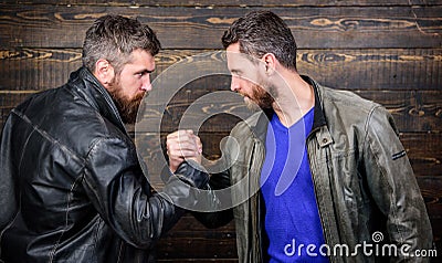 Brutal bearded men wear leather jackets shaking hands. Strong handshake. Friendship of brutal guys. Handshake symbol of Stock Photo