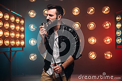 Brutal bearded singer with microphone on the stage Stock Photo