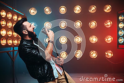 Brutal bearded singer with microphone on the stage Stock Photo