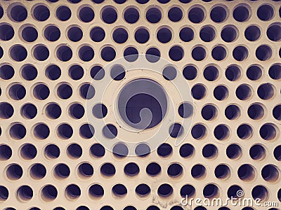 Brutal cement wall with a lot of small close-packed holes with copyspace in the central big hole. Abstract urban background. Stock Photo