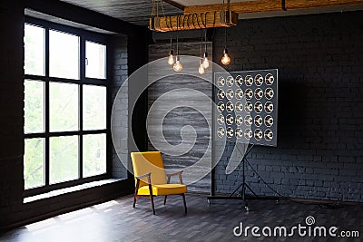 Brutal modern interior in a dark color with a yellow leather chair and big window. Loft style living room Stock Photo