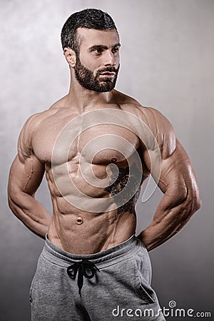 Brutal strong bodybuilder man posing in studio on grey background. Stock Photo