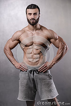 Brutal strong bodybuilder man posing in studio on grey background. Stock Photo