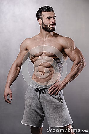 Brutal strong bodybuilder man posing in studio on grey background. Stock Photo