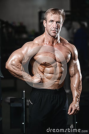 Brutal strong bodybuilder man pumping up muscles and train gym Stock Photo