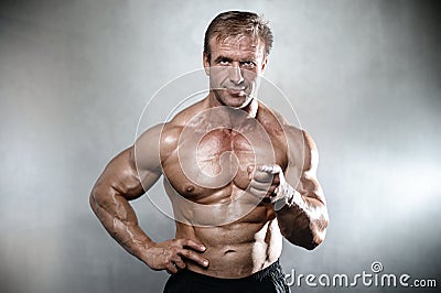 Brutal strong bodybuilder old man posing in studio grey background Stock Photo