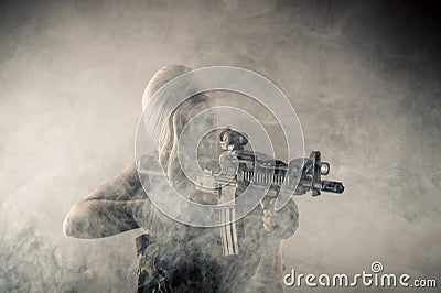 Brutal woman with gun in hands in smoke Stock Photo