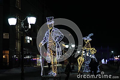 Bryansk, Russia - January 8, 2022: glowing figures of a lady and a gentleman in a hat on the city boulevard in the evening during Editorial Stock Photo