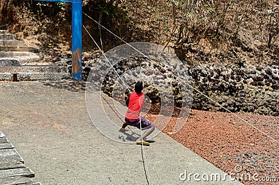 Unidentified local boy in red shirt pulls the rope in a village Editorial Stock Photo