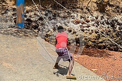 Unidentified local boy in red shirt pulls the rope in a village Editorial Stock Photo