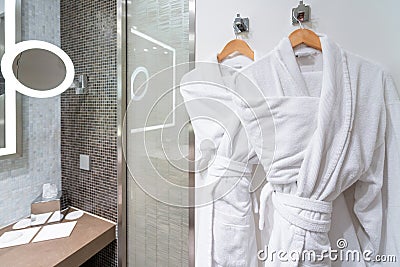 Bubble bath time : Clean White bathrobes on hanger in a bathroom. How to Keep Your Bathrobe Clean and Fluffy. - Always Spot Test. Stock Photo