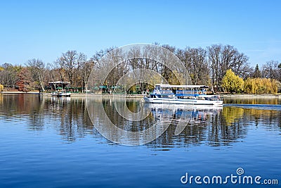 White boat on Herastrau lake and large green trees in King Michael I Park ( Editorial Stock Photo