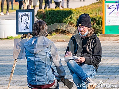 Street artist cartoonist or painter making portraits to people in Herestrau park Kink MIhai I, Editorial Stock Photo