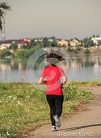 Young girl jogging in the morning. Woman working out on Lacul Morii or Windmill lake in Bucharest Editorial Stock Photo