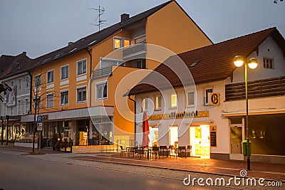 BUCHLOE, GERMANY - OKTOBER 09, 2018: Light from a cafe on an empty street in the morning in Buchloe Germany Editorial Stock Photo