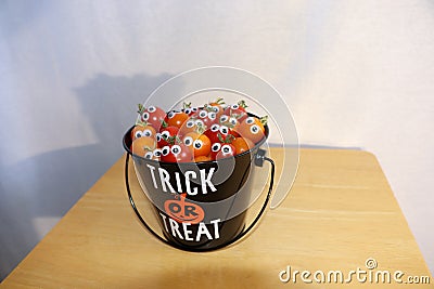 A bucket full of small tomatoes with googly eyes are treats for Halloween. Stock Photo