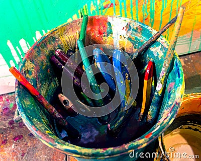 Bucket full of multi-colored brushes soaked in the artist`s studio Stock Photo