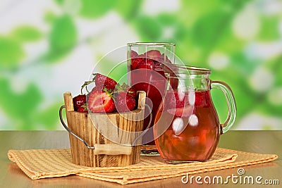 Bucket strawberries, glass, jug with drink, wipes on abstract green . Stock Photo