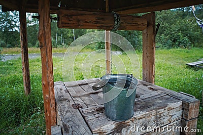 A bucket for water on an old traditional well dug in the ground for the extraction of clean water Stock Photo