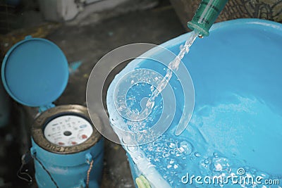 Bucket with water overflowing. And water meter behind scene. Stock Photo