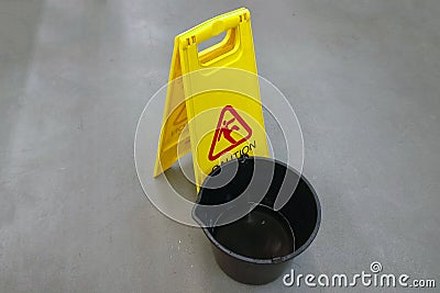 A bucket of water and a sign - carefully slippery floor. Copyspace for lettering. Caution can slip, the floor is slippery Stock Photo