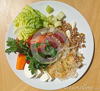 Buckwheat porridge with mocarella cheese, sauerkraut, garlic, cooked and raw colorful vegetables. Stock Photo