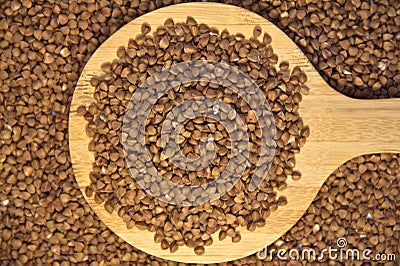 Buckwheat on a wooden kitchen spoon. Against the background of buckwheat Stock Photo