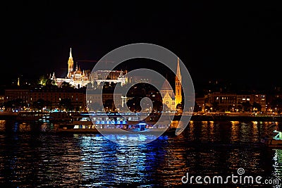 Budapest night landscape with lots of lanterns and illuminated buildings. A pleasure boat is sailing on the river Editorial Stock Photo