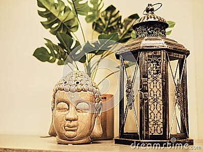 Buddah statue in modern home, Home decoration. Candle Lighter and Buddha Head statue and Monstera's Leaves. Holidays decoration Stock Photo